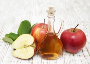 Apples and apple cider vinegar on a wood table