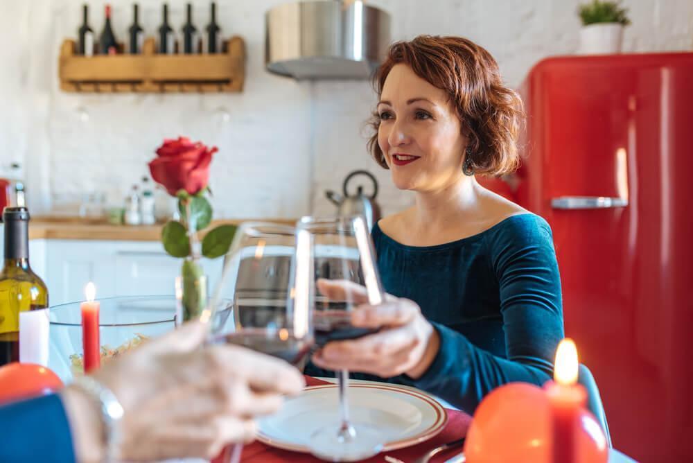 woman clinking wine glass with unseen man