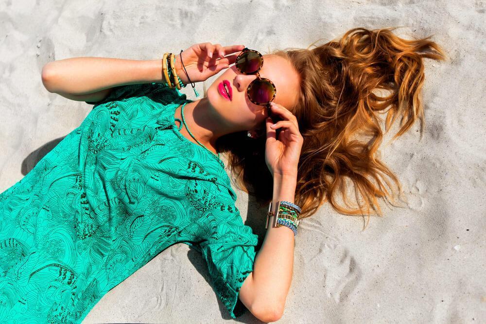 Young woman in sunglasses and a green tunic on the beach