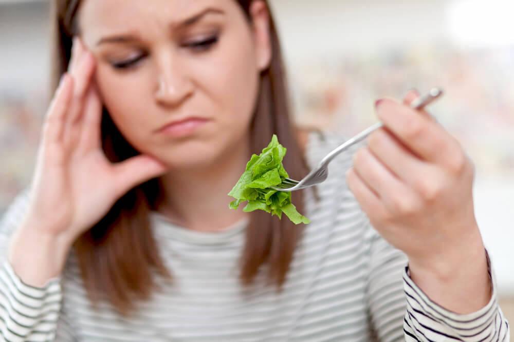 Unhappy woman looking at her salad