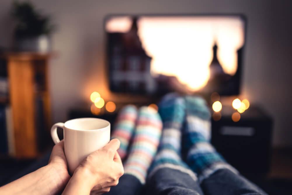 Two people with socks and mug watching TV