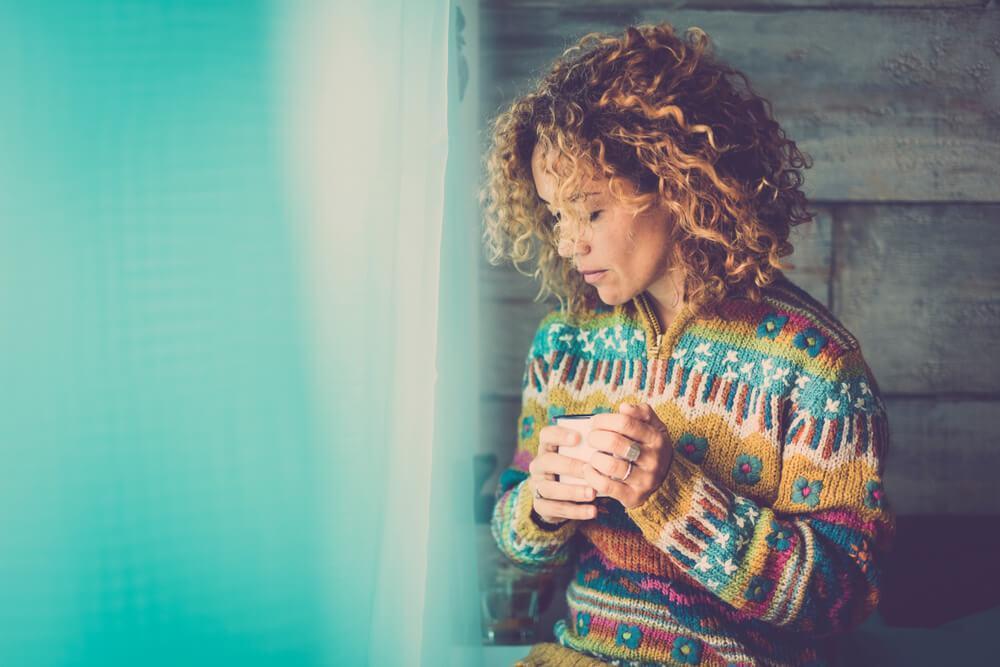 Woman standing by window looking sad