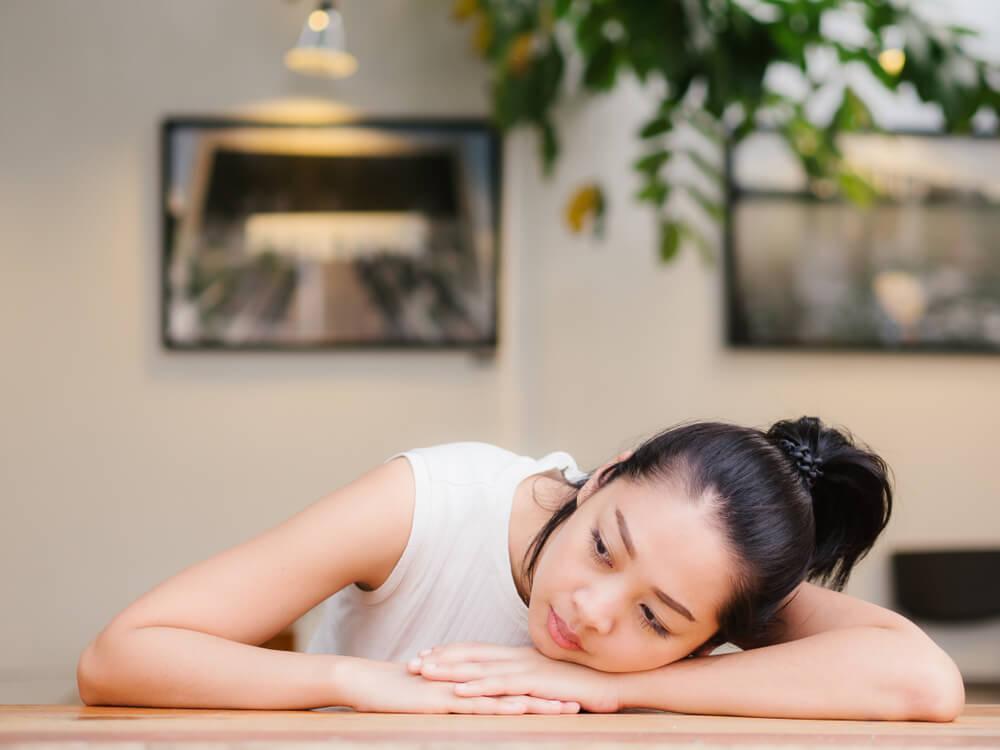 Woman sitting with head on arms