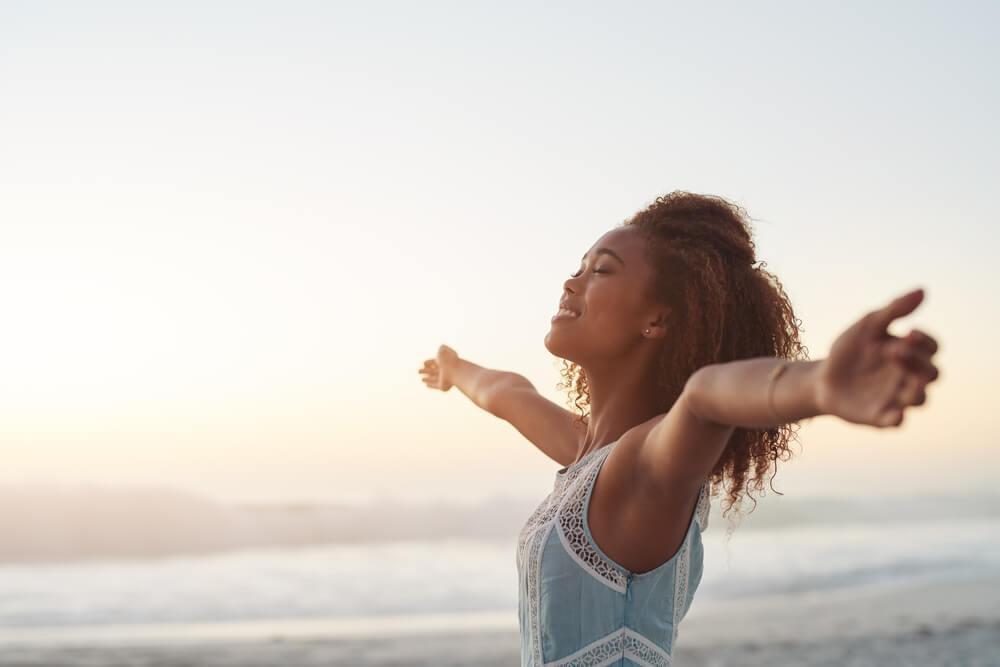 Woman standing with arms stretched by sea