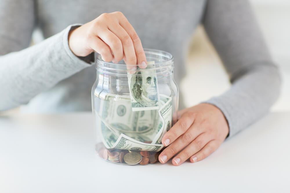 Woman placing money into a jar