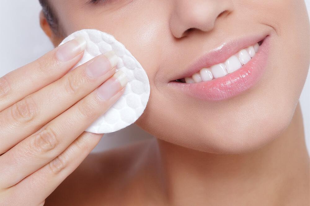 Close-up of woman cleansing face with cotton pad