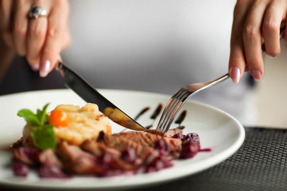 Close-up of hands, cutlery and plate