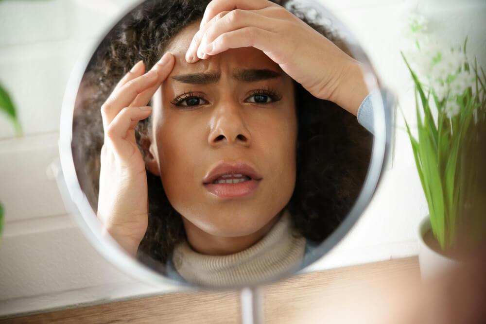 Woman squeezing spot in mirror