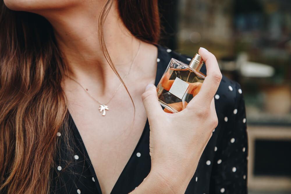 Woman spraying perfume outdoors