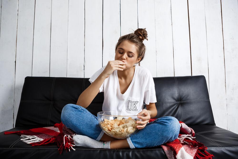 Woman eating chips on sofa