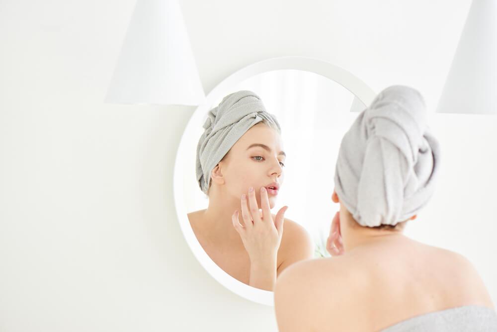 Woman looking at skin in mirror