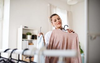 Woman holding clothes up in front of mirror to decide on the best clothing colors for her skin undertone